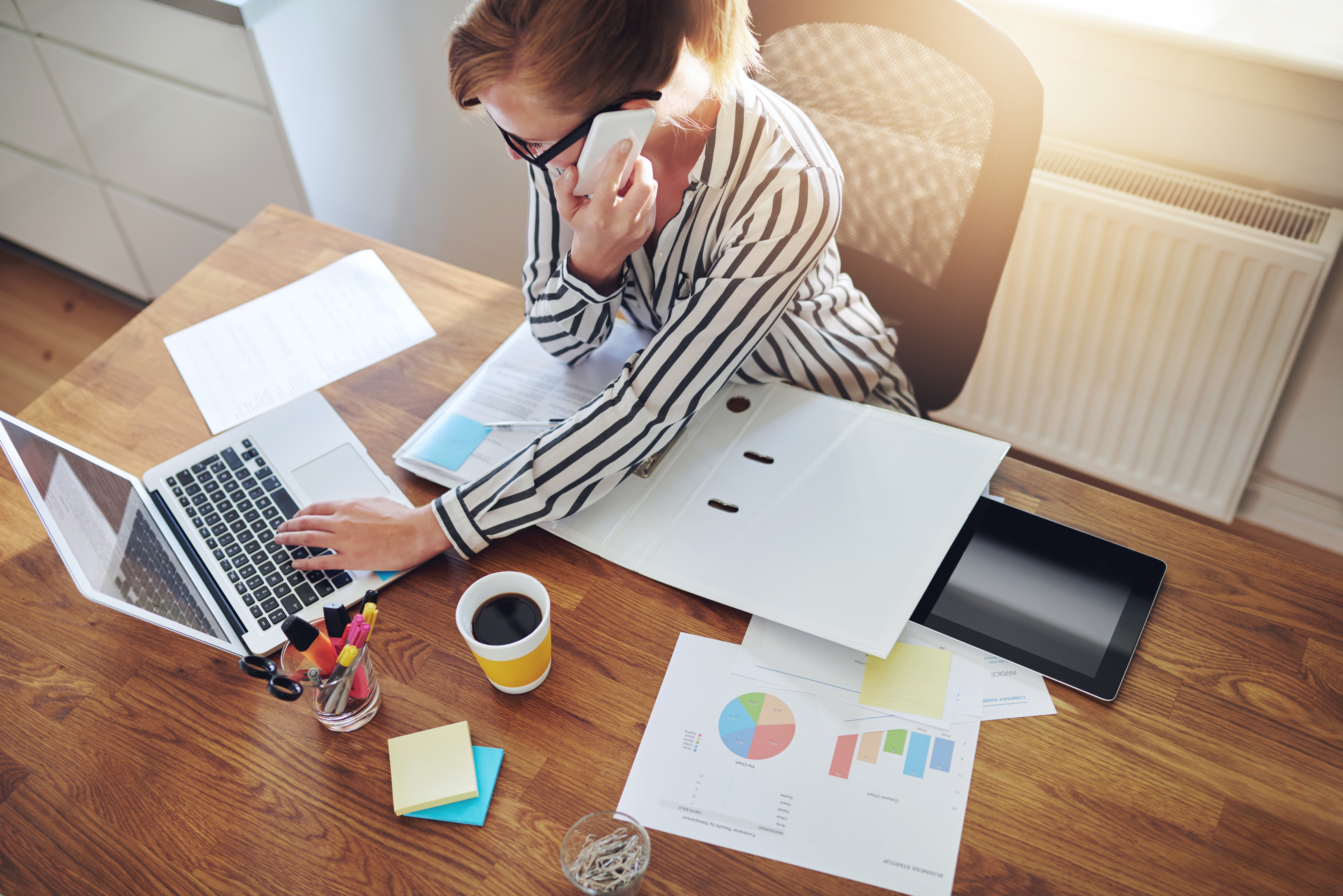 Successful businesswoman with an e-business working from an office at home telemarketing and taking orders over the phone or consulting with clients, high angle view